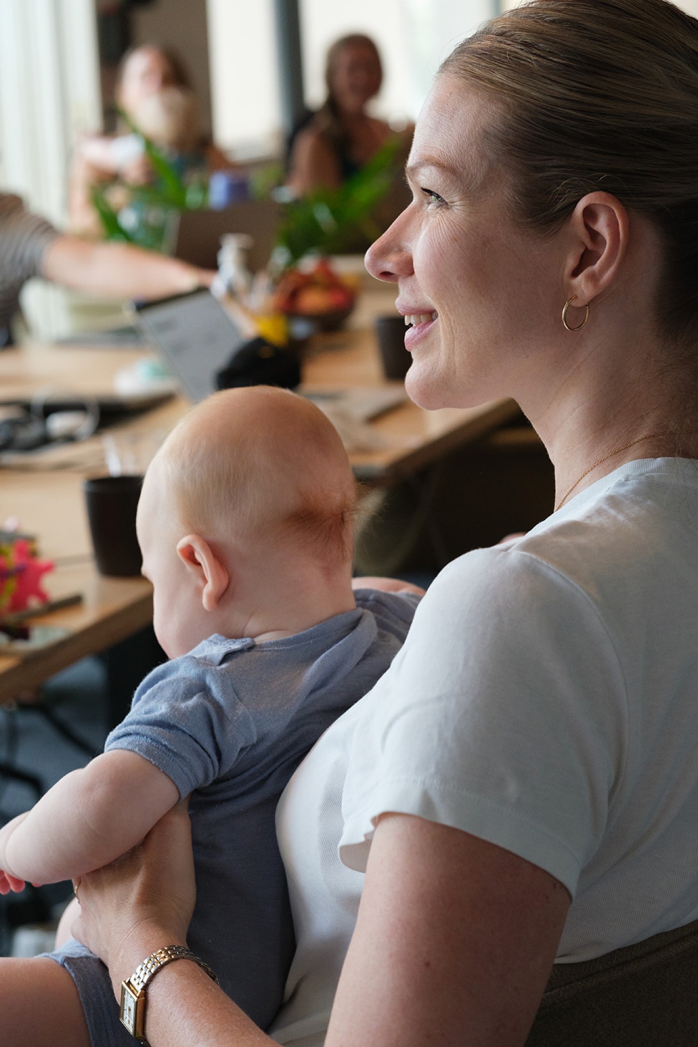 A mum smiling in profile, holding her baby at the pilot