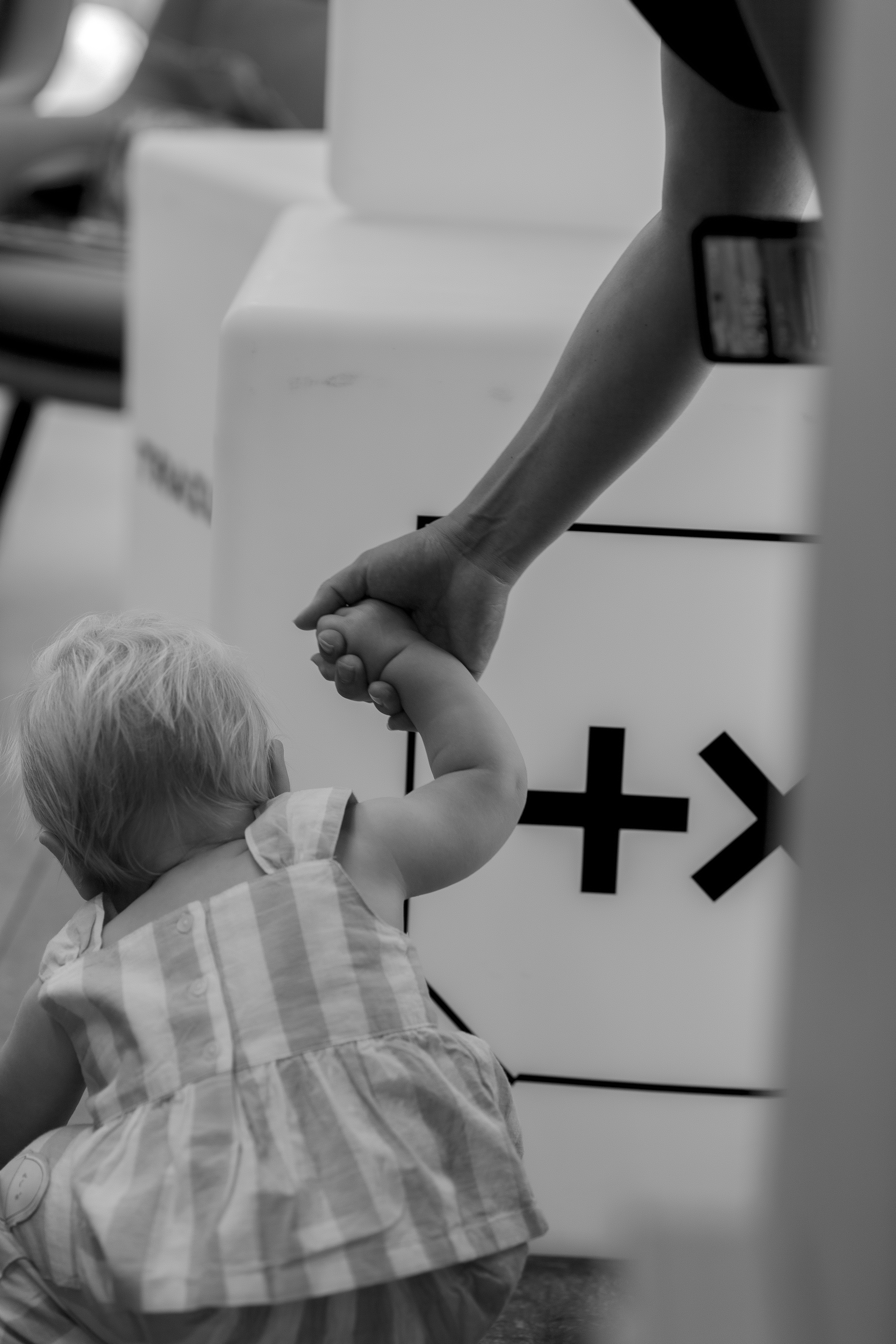 A baby holding a grown-up's hand beside the Plus X Innovation branding, our Brighton venue partner